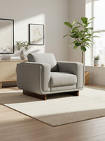 Fauteuil Simone TOCO Meubles gris en tissu texturé avec base en bois massif dans un salon lumineux et moderne