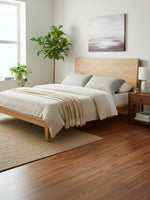 Grand lit TOCO Meubles Carmen en bois clair avec tête de lit inclinable et ports USB dans une chambre minimaliste