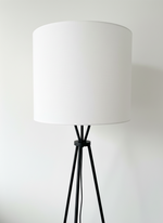 Lampadaire TOCO Meubles Ambrose avec structure en métal noir et grand abat-jour cylindrique en tissu blanc
