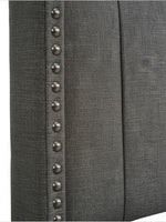 Gros plan sur la tête de lit TOCO Meubles Dante en tissu gris effet lin avec clous décoratifs argentés.