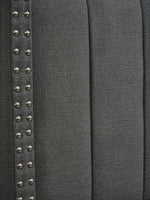 Gros plan sur la tête de lit TOCO Meubles Dante en tissu gris effet lin avec détails de clous décoratifs argentés.