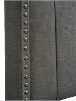 Gros plan sur la tête de lit TOCO Meubles Dante en tissu gris effet lin avec clous décoratifs argentés.