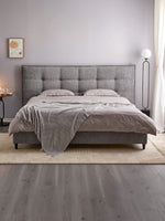 TOCO Meubles Lit Guilia gris en tissu bouclé capitonné avec coutures passepoilées et pieds en acier noir.