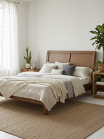 Très grand lit plateforme TOCO Meubles Antoine en bois brun clair avec tête de lit style traîneau dans une chambre