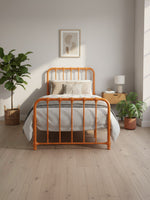 Lit simple Daisy TOCO Meubles en métal orange vif au design vintage avec tête et pied de lit arrondis dans une chambre