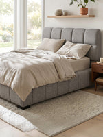Grand lit Sofia TOCO Meubles gris clair capitonné en tissu texturé avec tête de lit imposante dans une chambre chic