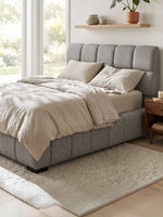 Grand lit Sofia TOCO Meubles gris clair capitonné en tissu texturé avec tête de lit imposante dans une chambre chic