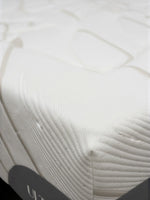 Gros plan sur le coin du matelas Ultra Firm de TOCO Meubles avec tissu blanc texturé et bordure grise