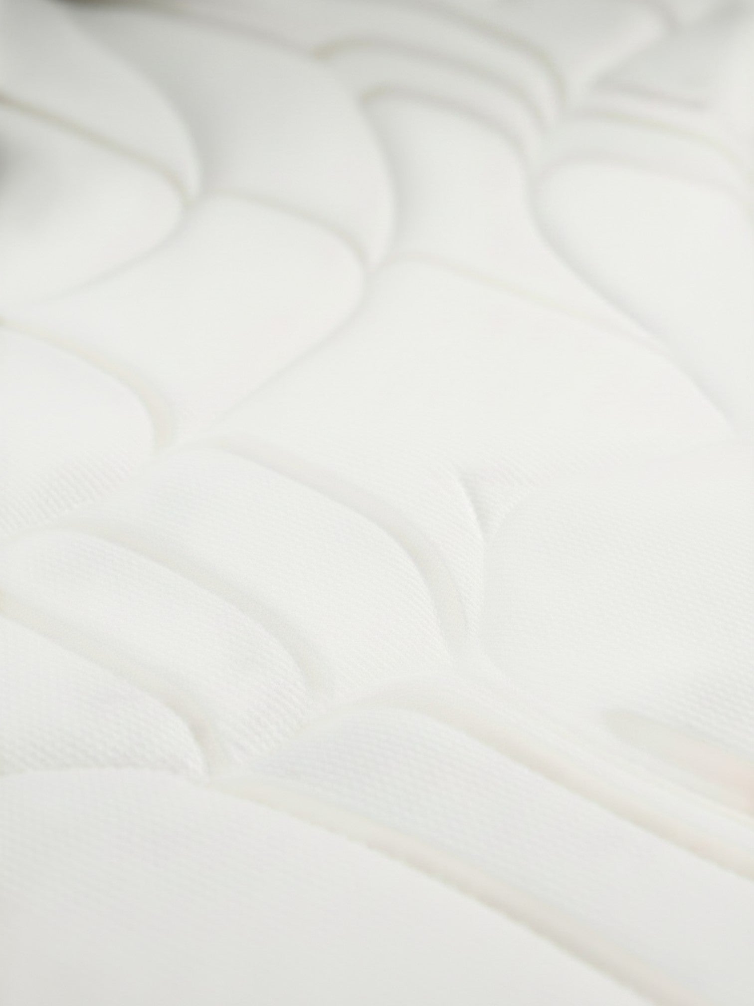 Gros plan sur le tissu blanc rafraîchissant et le matelassage ferme du matelas Ultra Firm de TOCO Meubles