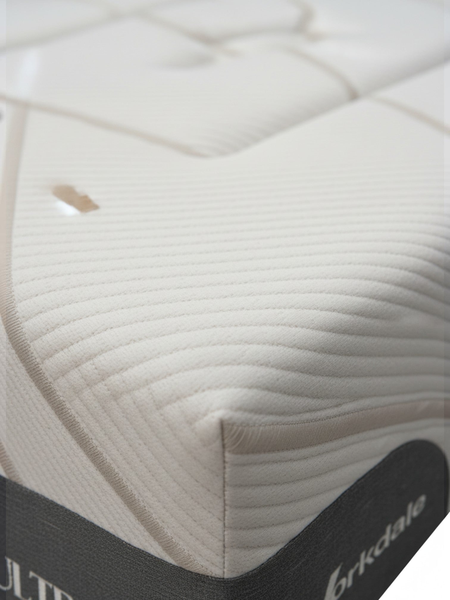 Gros plan sur le matelas Ultra Plush de TOCO Meubles avec son tissu matelassé blanc texturé et ses coutures élégantes