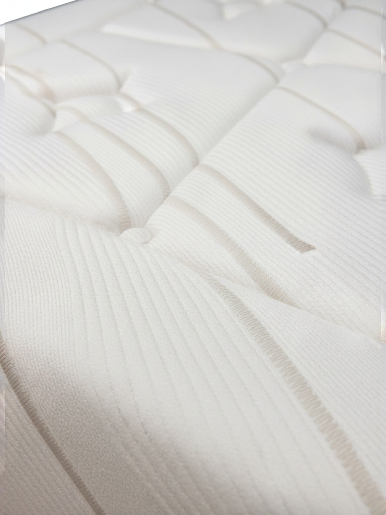Gros plan sur le tissu matelassé blanc et doux du matelas Ultra Plush de TOCO Meubles avec détails texturés