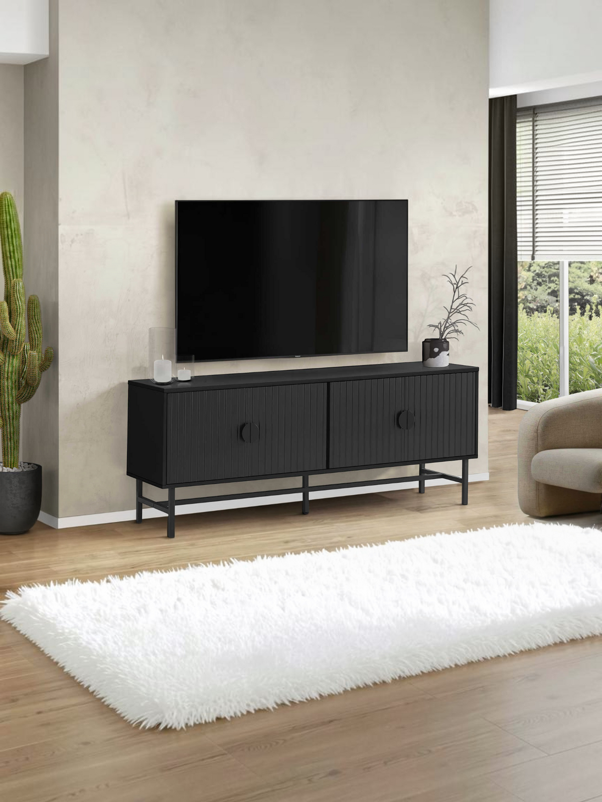 Meuble télé noir Clara de TOCO Meubles avec portes rainurées et pieds en métal dans un salon moderne