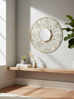 Miroir mural rond TOCO Meubles Horus avec cadre métallique doré géométrique inspiré du soleil sur un mur clair