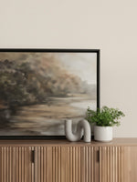 Objet décoratif Kailas en béton gris par TOCO Meubles posé sur un buffet en bois à côté d'une plante verte
