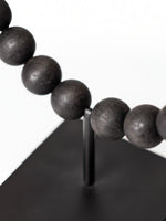 Objet décoratif TOCO Meubles Tulane, sphère brisée composée de perles noires mates sur un support métallique noir.
