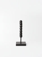 Objet décoratif TOCO Meubles Tulane composé d'une colonne de perles noires texturées sur un socle carré noir