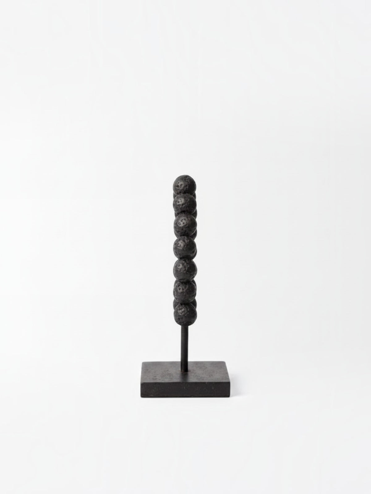 Objet décoratif TOCO Meubles Tulane composé d'une colonne de perles noires texturées sur un socle carré noir