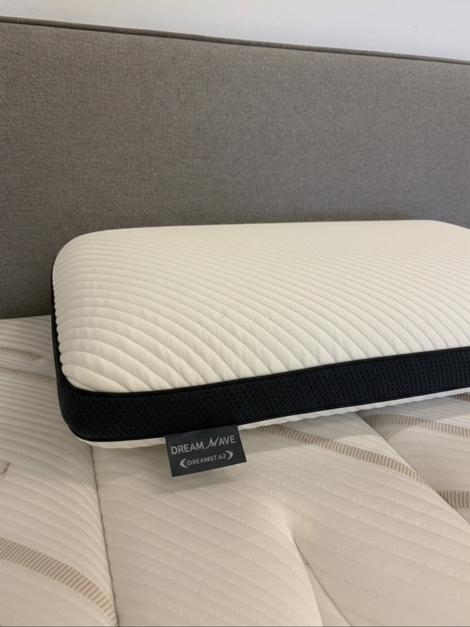 Oreiller ergonomique TOCO Meubles Dreamwave blanc avec bordure noire respirante posé sur un matelas