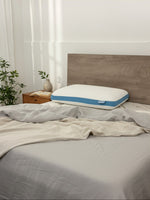 Oreiller Dreamwave Gel TOCO Meubles ergonomique et rafraîchissant posé sur un lit avec draps en lin gris