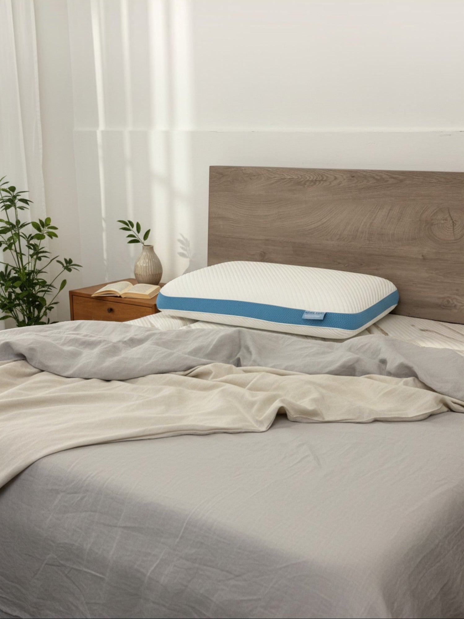 Oreiller Dreamwave Gel TOCO Meubles ergonomique et rafraîchissant posé sur un lit avec draps en lin gris