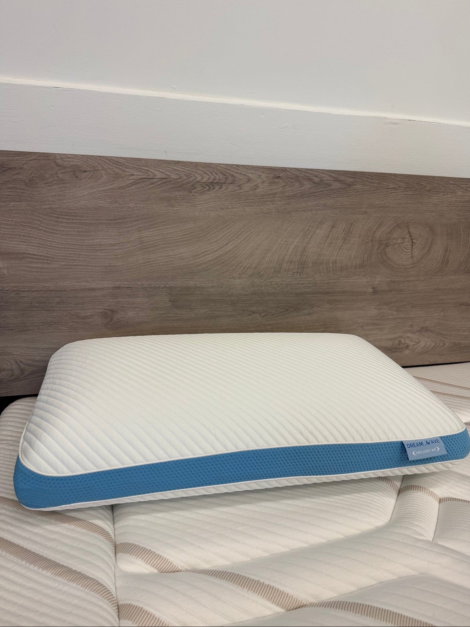 Oreiller ergonomique TOCO Meubles Dreamwave Gel blanc avec bande latérale bleue rafraîchissante sur un matelas