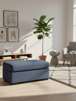Ottoman Evan bleu en tissu texturé dans un salon moderne avec tapis et plante, par TOCO Meubles