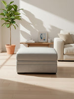 Ottoman Ugo de TOCO Meubles en tissu gris ciment avec rangement dans un salon lumineux et moderne