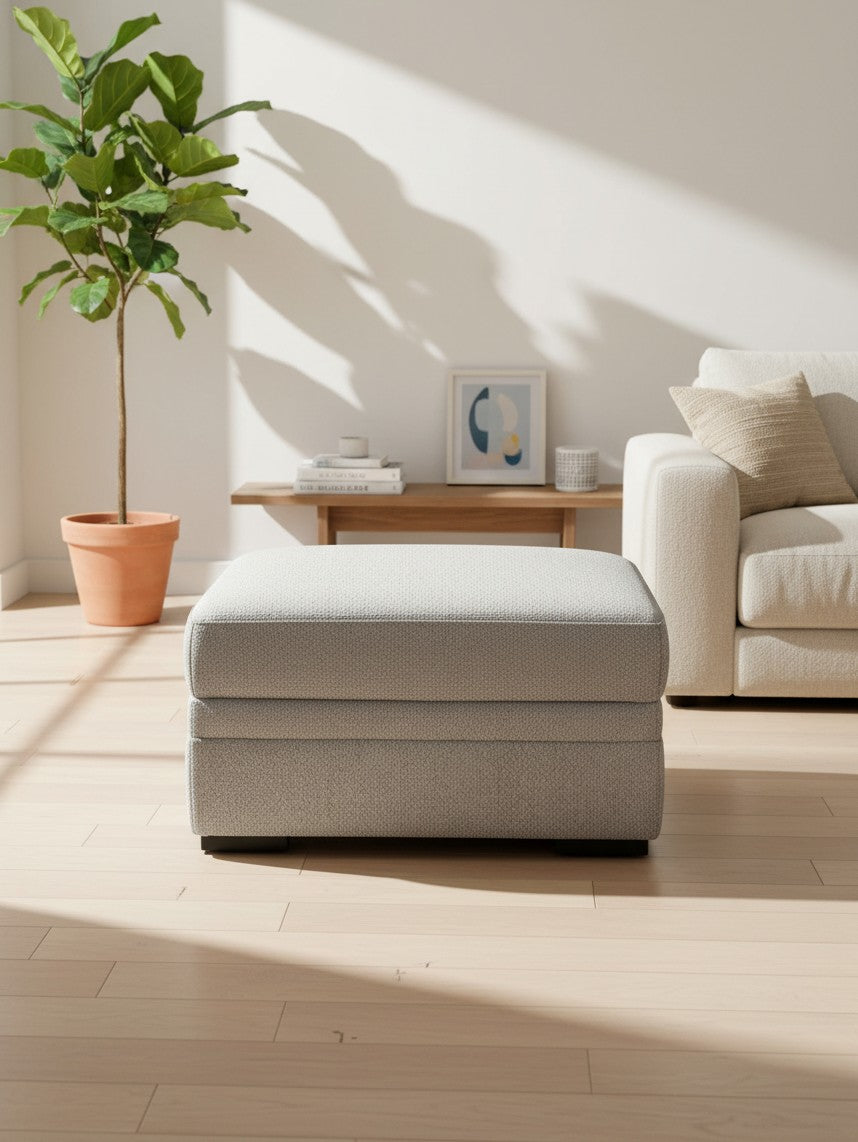 Ottoman Ugo de TOCO Meubles en tissu gris ciment avec rangement dans un salon lumineux et moderne