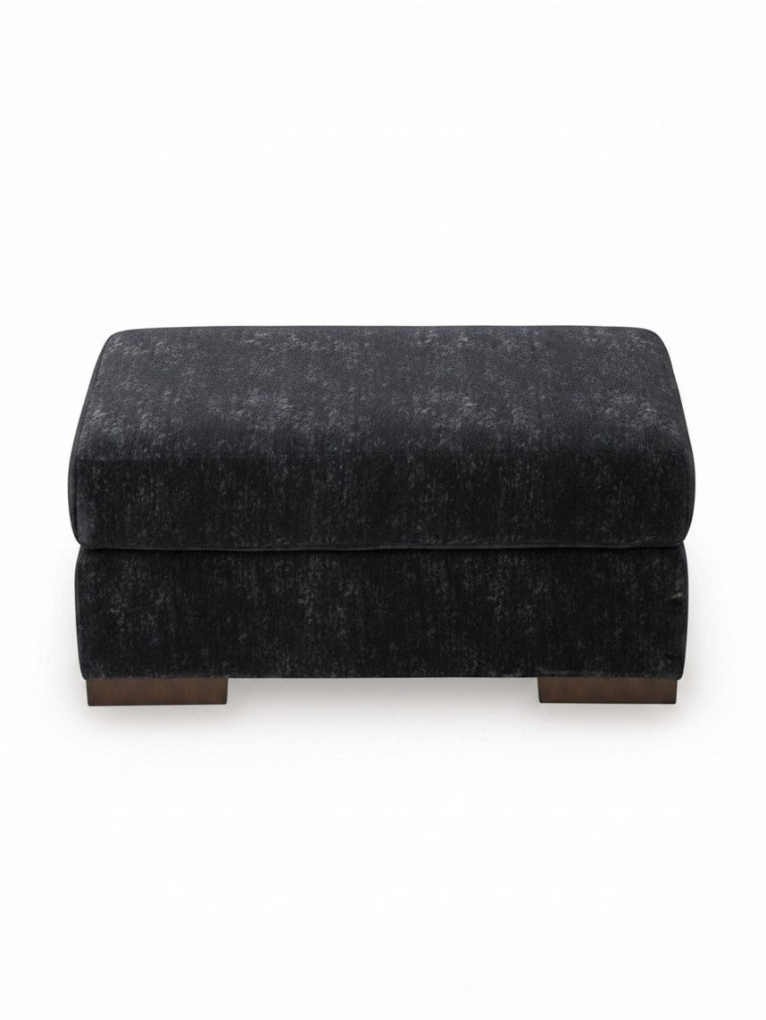 Ottoman Mistral de TOCO Meubles en tissu texturé gris foncé avec pieds en bois massif sur fond blanc