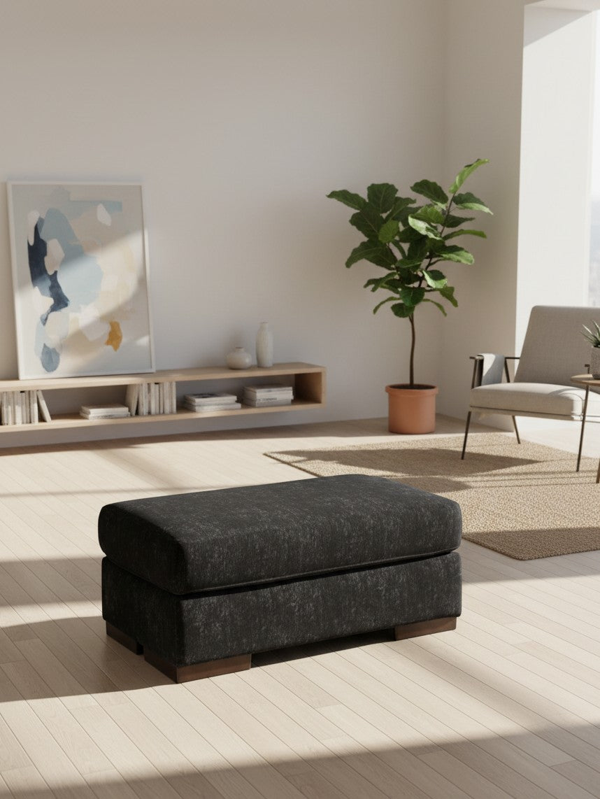 Ottoman Mistral de TOCO Meubles en tissu gris anthracite avec base en bois dans un salon moderne et lumineux