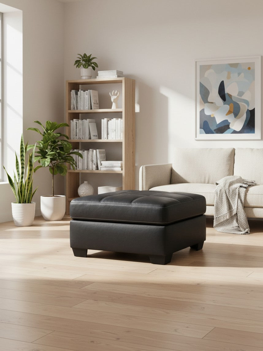 Ottoman surdimensionné TOCO Meubles Marlin en cuir noir avec coutures apparentes dans un salon moderne