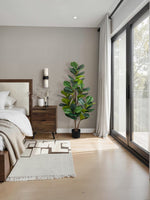 Plante artificielle Kami TOCO Meubles avec feuillage vert luxuriant dans un pot noir, installée dans une chambre.