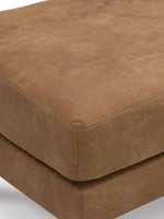 Gros plan sur le pouf TOCO Meubles Telora en cuir caramel avec des coutures apparentes élégantes