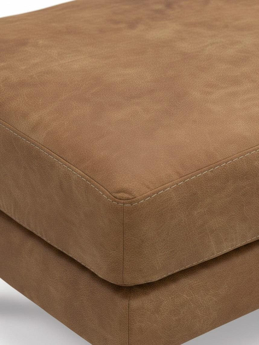 Gros plan sur le pouf TOCO Meubles Telora en cuir caramel avec des coutures apparentes élégantes