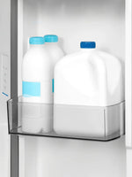 Bacs de porte ajustables du réfrigérateur MIDEA chez TOCO Meubles contenant des bouteilles et un pichet de lait