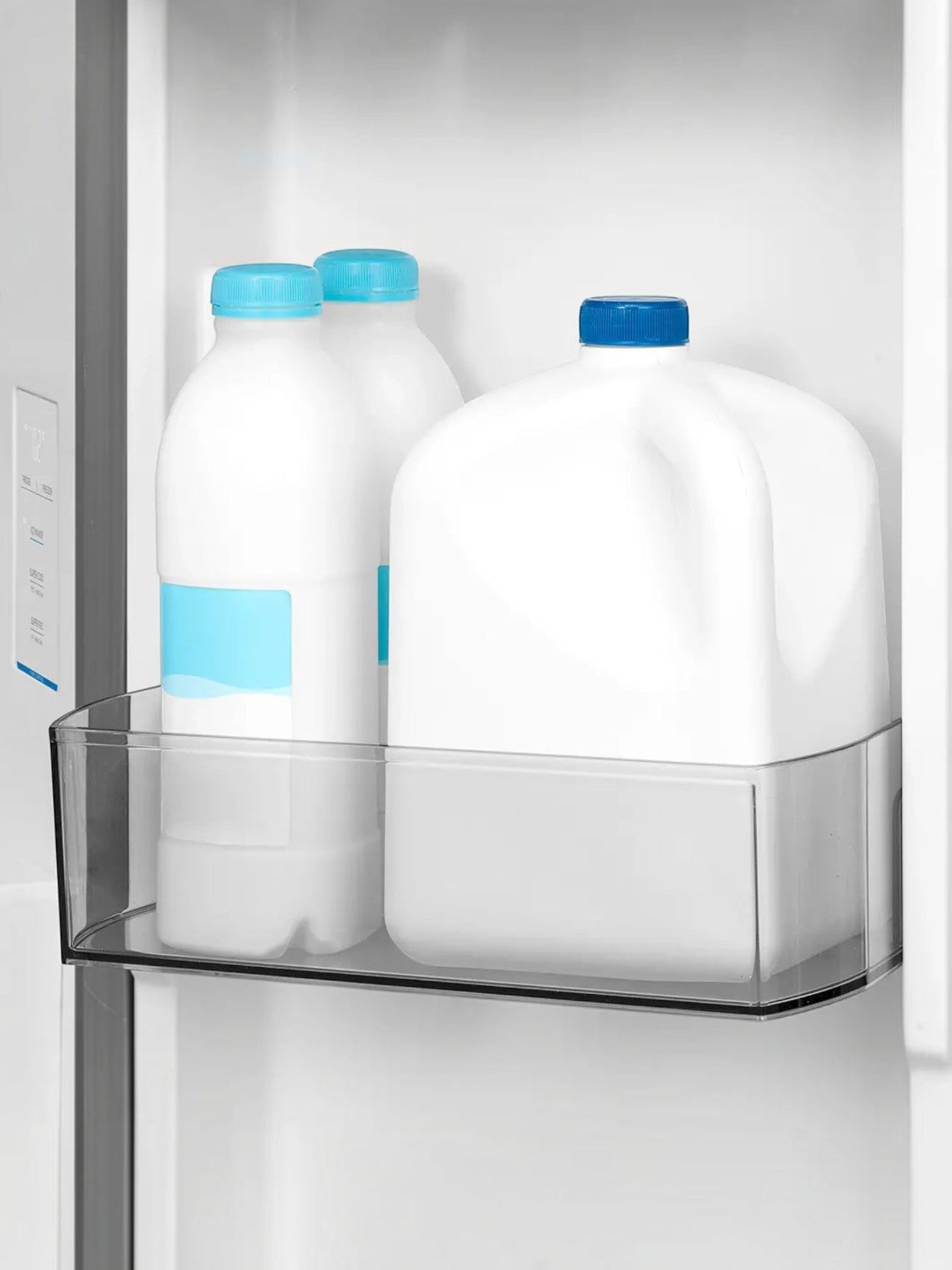 Bacs de porte ajustables du réfrigérateur MIDEA chez TOCO Meubles contenant des bouteilles et un pichet de lait