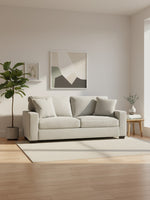 Sofa Aldo de TOCO Meubles en tissu texturé beige clair dans un salon lumineux avec plante et décoration murale