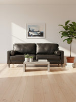 Sofa Bryce TOCO Meubles en cuir noir avec coussins cylindriques dans un salon moderne et lumineux