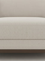 Gros plan sur le tissu beige texturé du sofa sectionnel Calvi de TOCO Meubles avec base en bois foncé
