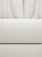 Gros plan sur le tissu texturé beige clair du canapé Figaro de TOCO Meubles avec des coussins rayés en arrière-plan
