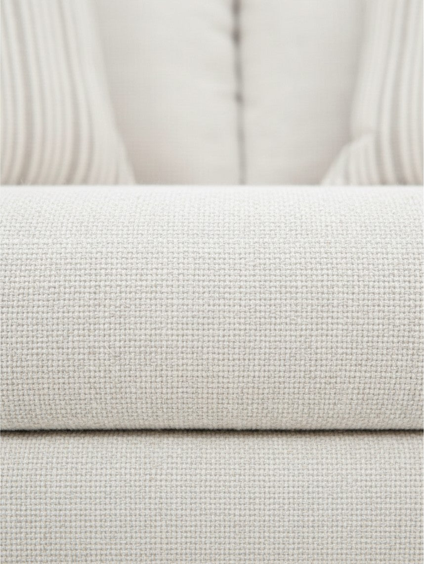 Gros plan sur le tissu texturé beige clair du canapé Figaro de TOCO Meubles avec des coussins rayés en arrière-plan