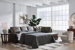 TOCO Meubles Sofa-lit Zuri marron aspect cuir avec lit déplié, coussins gris et décorations modernes.