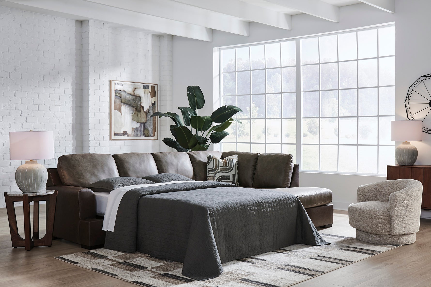 TOCO Meubles Sofa-lit Zuri marron aspect cuir avec lit déplié, coussins gris et décorations modernes.