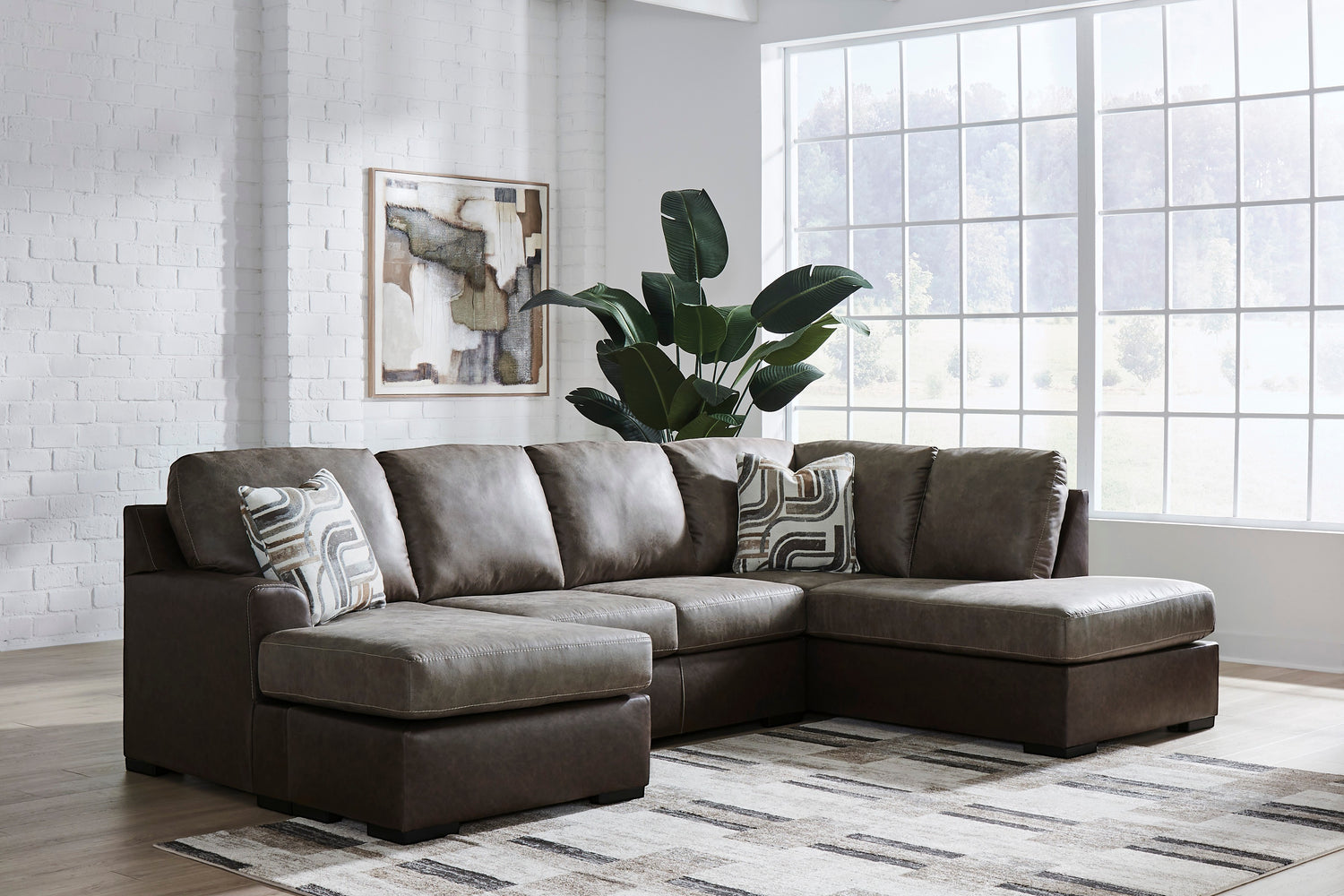 TOCO Meubles Sofa-lit Zuri sectionnel en cuir brun foncé avec coussins décoratifs géométriques.