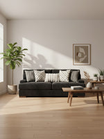 Sofa Mistral de TOCO Meubles en tissu noir avec coussins décoratifs dans un salon moderne et lumineux