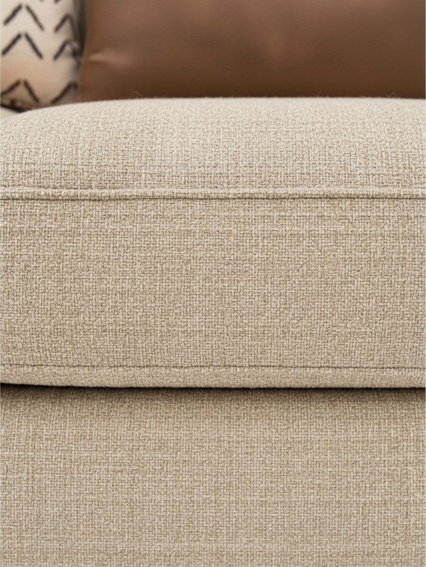 Gros plan sur le revêtement en tissu beige texturé du sofa modulaire Kelso de TOCO Meubles avec coussins décoratifs