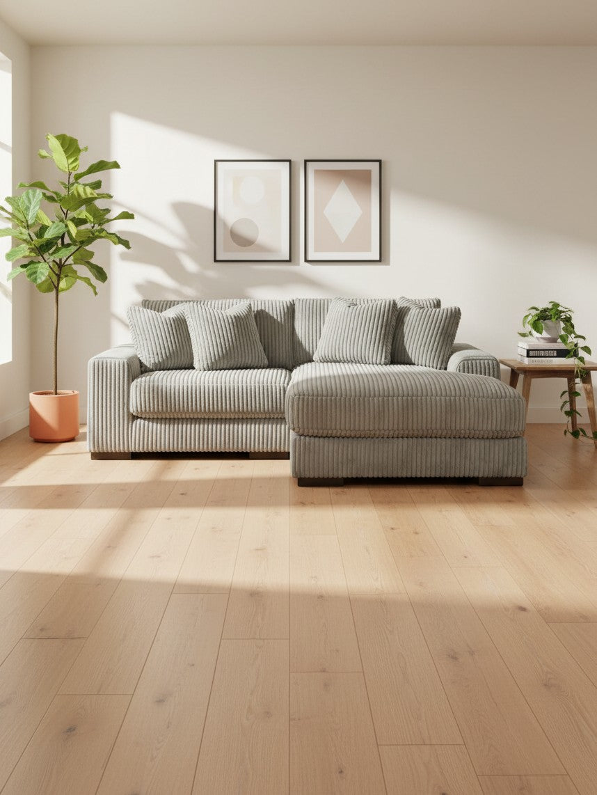 Sofa modulaire Manoa en velours côtelé gris clair de TOCO Meubles dans un salon lumineux avec plantes vertes.
