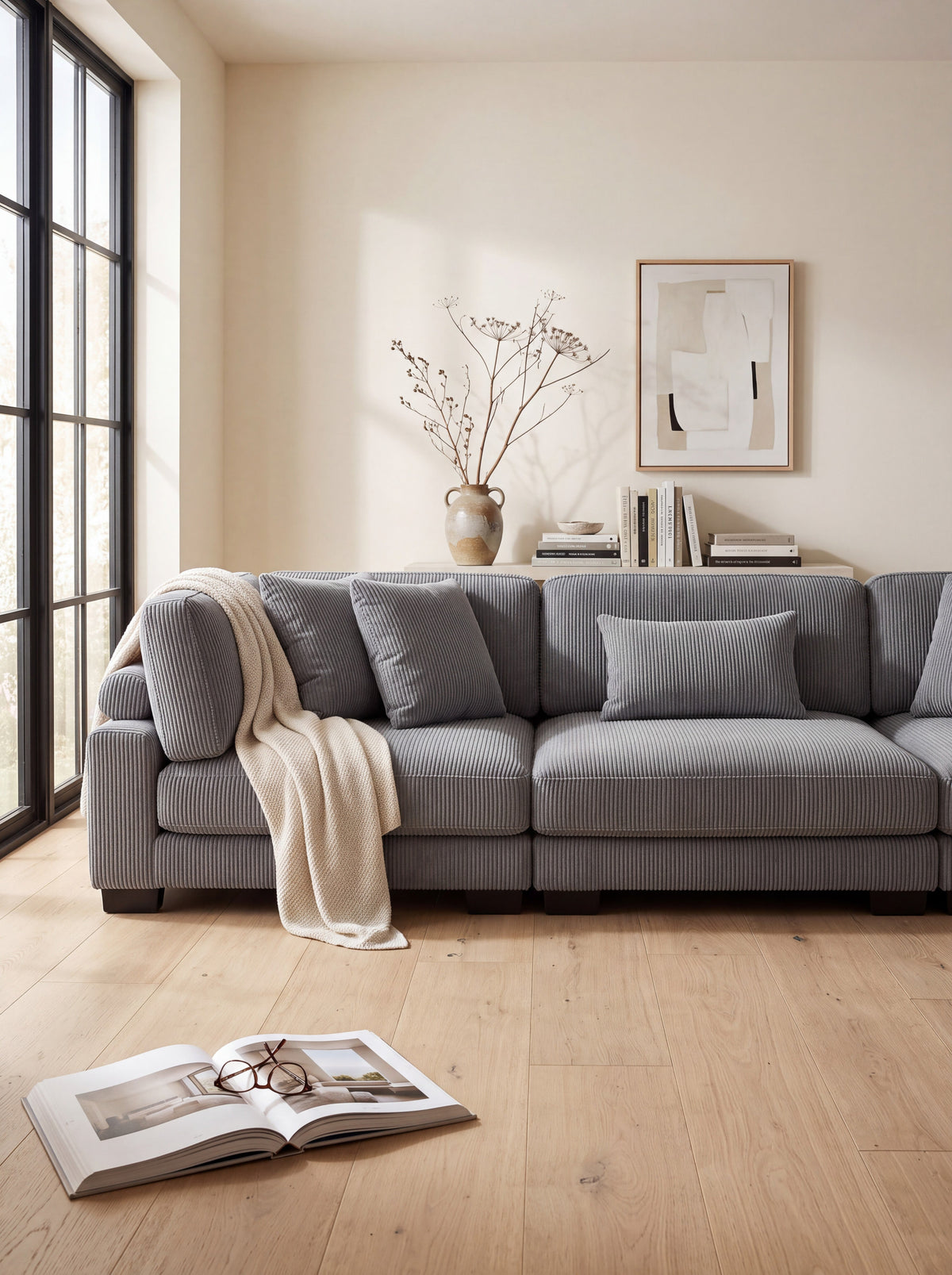 Sofa modulaire gris en velours côtelé TOCO Meubles avec coussins et jeté beige dans un salon lumineux