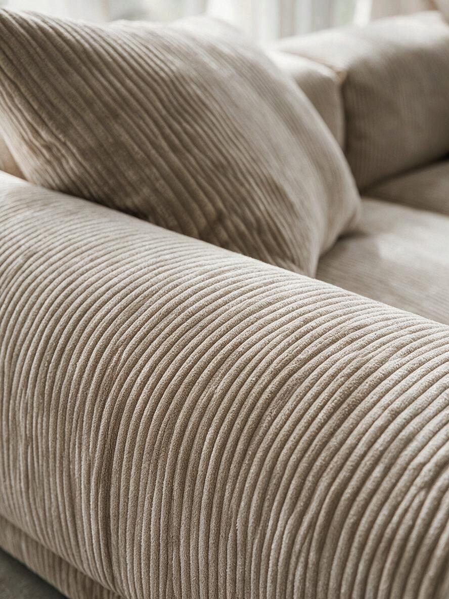 Sofa modulaire Nola beige en velours côtelé avec ottoman, présenté dans un salon lumineux par TOCO Meubles