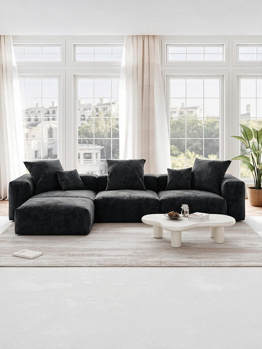 Sofa modulaire Nola de TOCO Meubles en velours côtelé noir avec ottoman dans un salon lumineux et moderne.